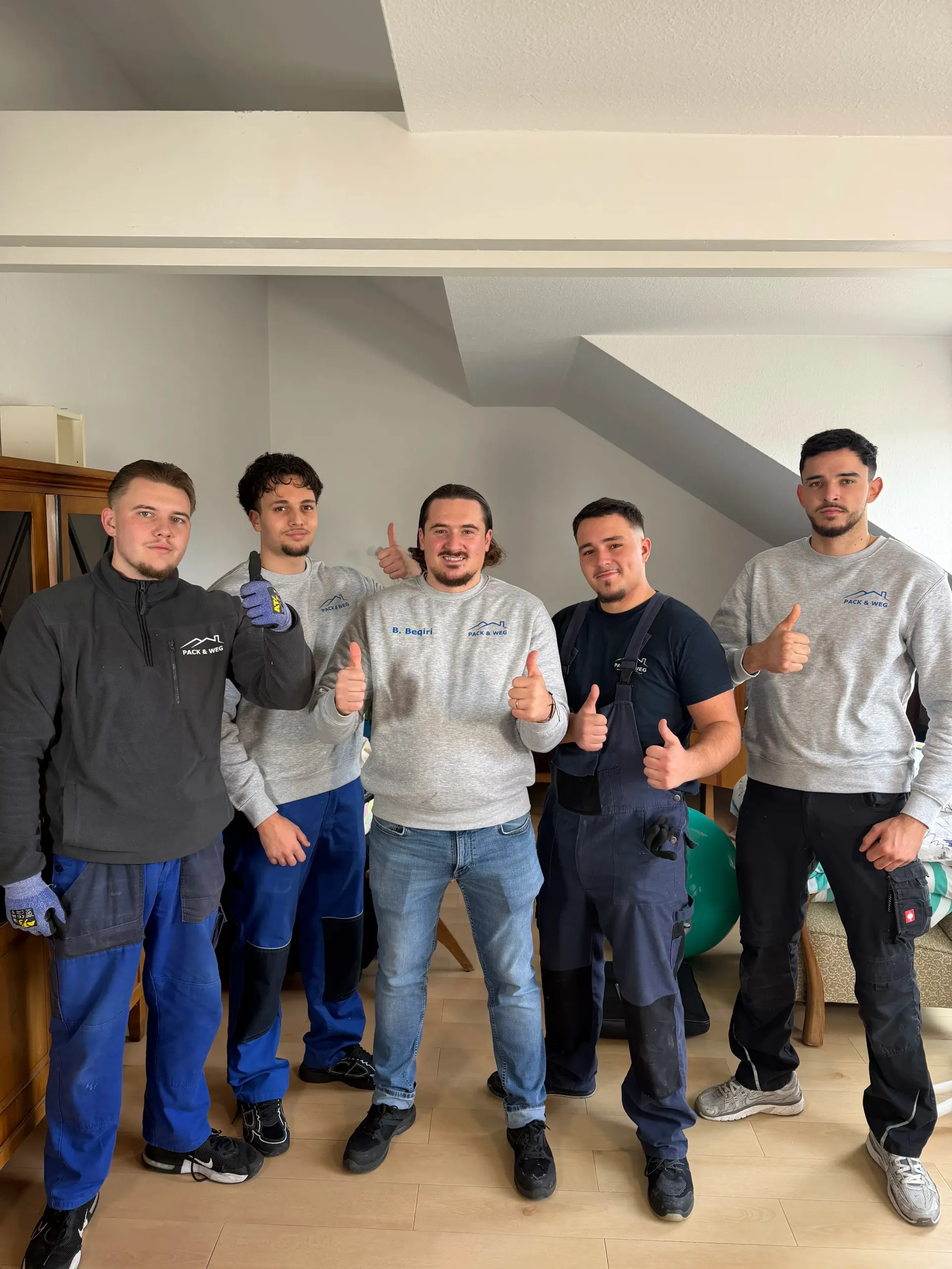 Sechs Personen in Arbeitskleidung zeigen drinnen den Daumen nach oben.