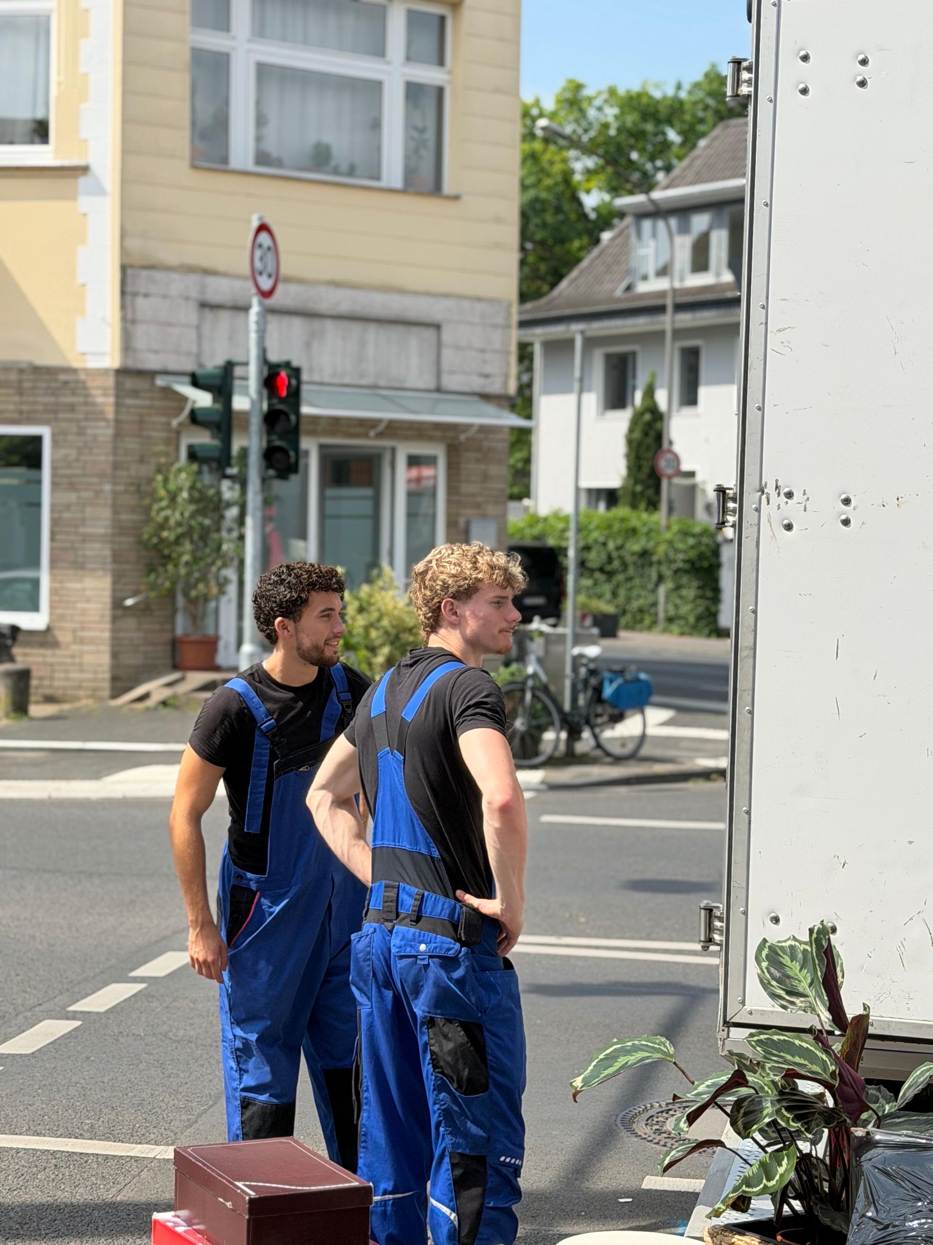 In einem modernen, sonnigen Loft mit großen Fenstern und Blick auf die Stadt sind neben einem Sofa gestapelte Kisten.