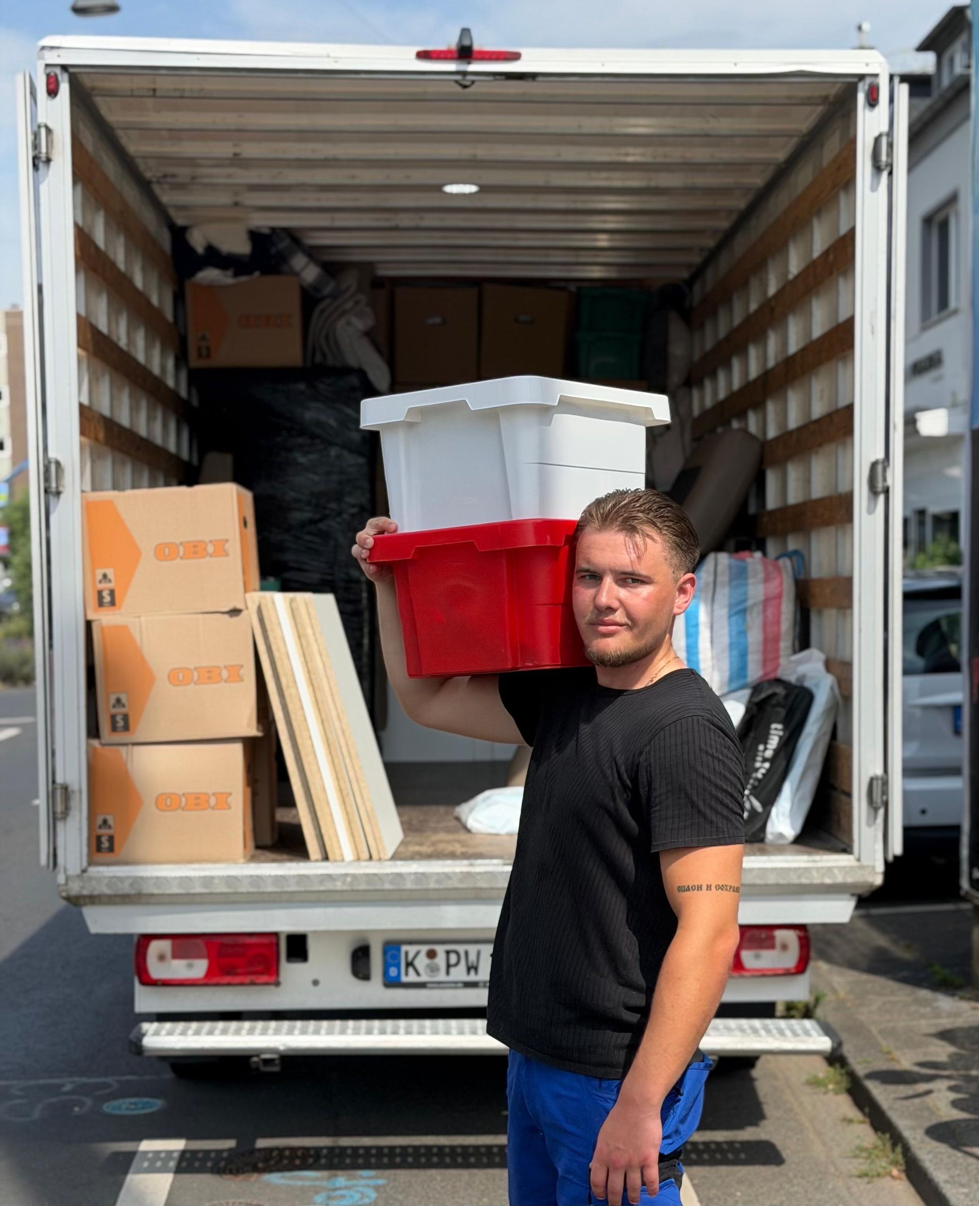 Büro wird umgezogen: Schreibtisch, Stühle, Kisten und in Plastik eingewickelte Möbel an den Fenstern.