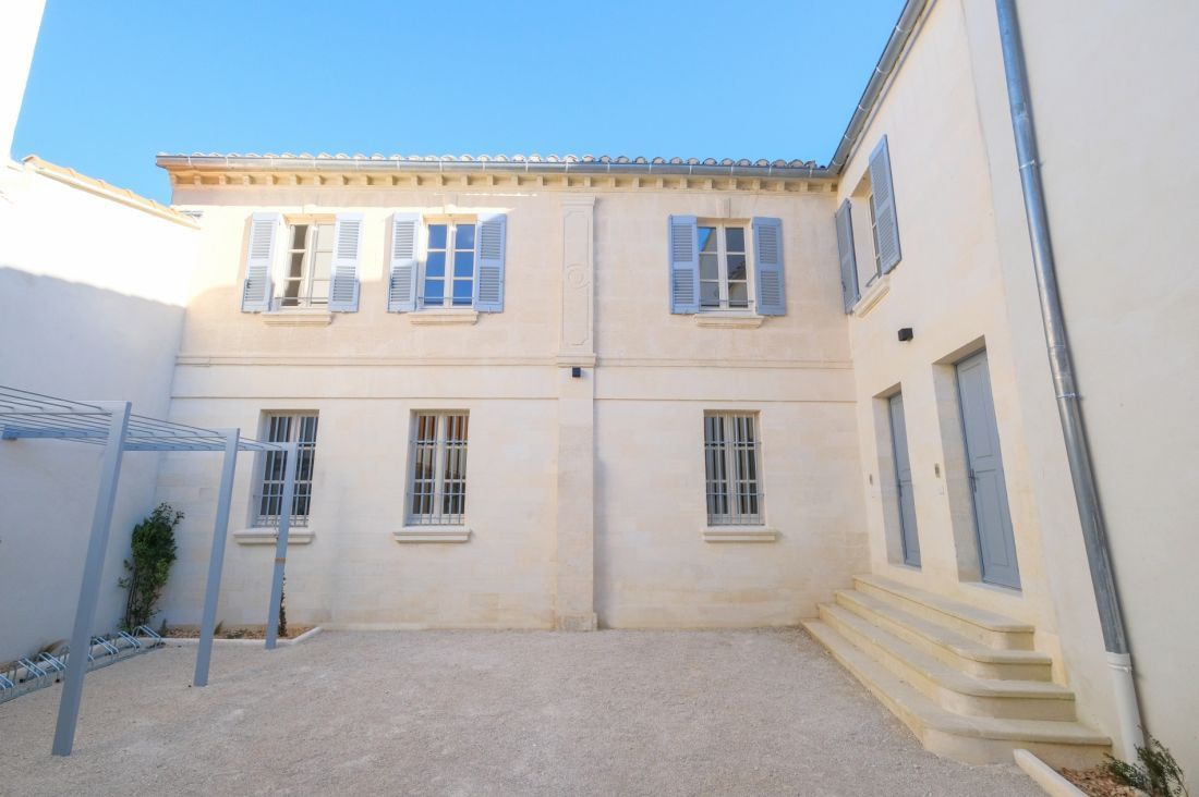 Extérieur d'un bâtiment de deux étages de couleur claire avec des volets et des portes bleus.