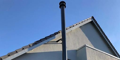 Ein Schornstein an der Seite eines Hauses mit einem blauen Himmel im Hintergrund.