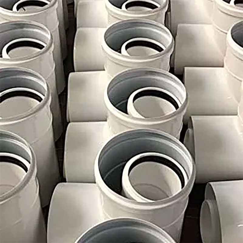 Auf einem Tisch sind mehrere weiße Plastikrohre übereinander gestapelt.