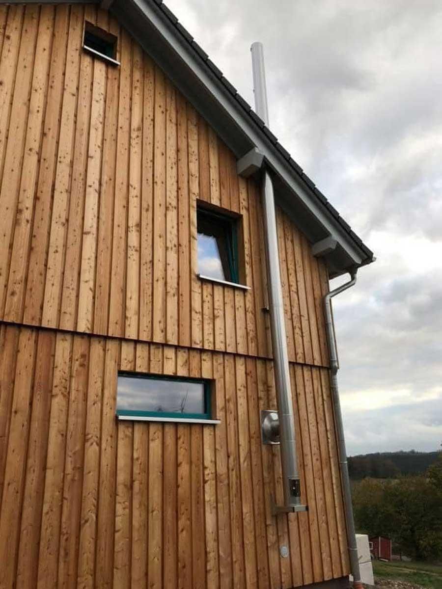 Ein Holzhaus mit einem Schornstein an der Seite