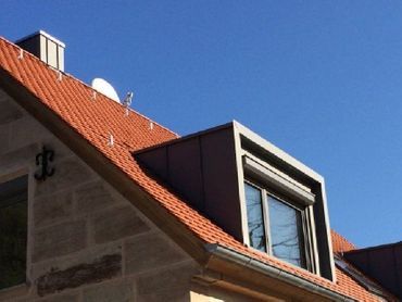 Mann mit Sicherheitsausrüstung bohrt ein Dach an