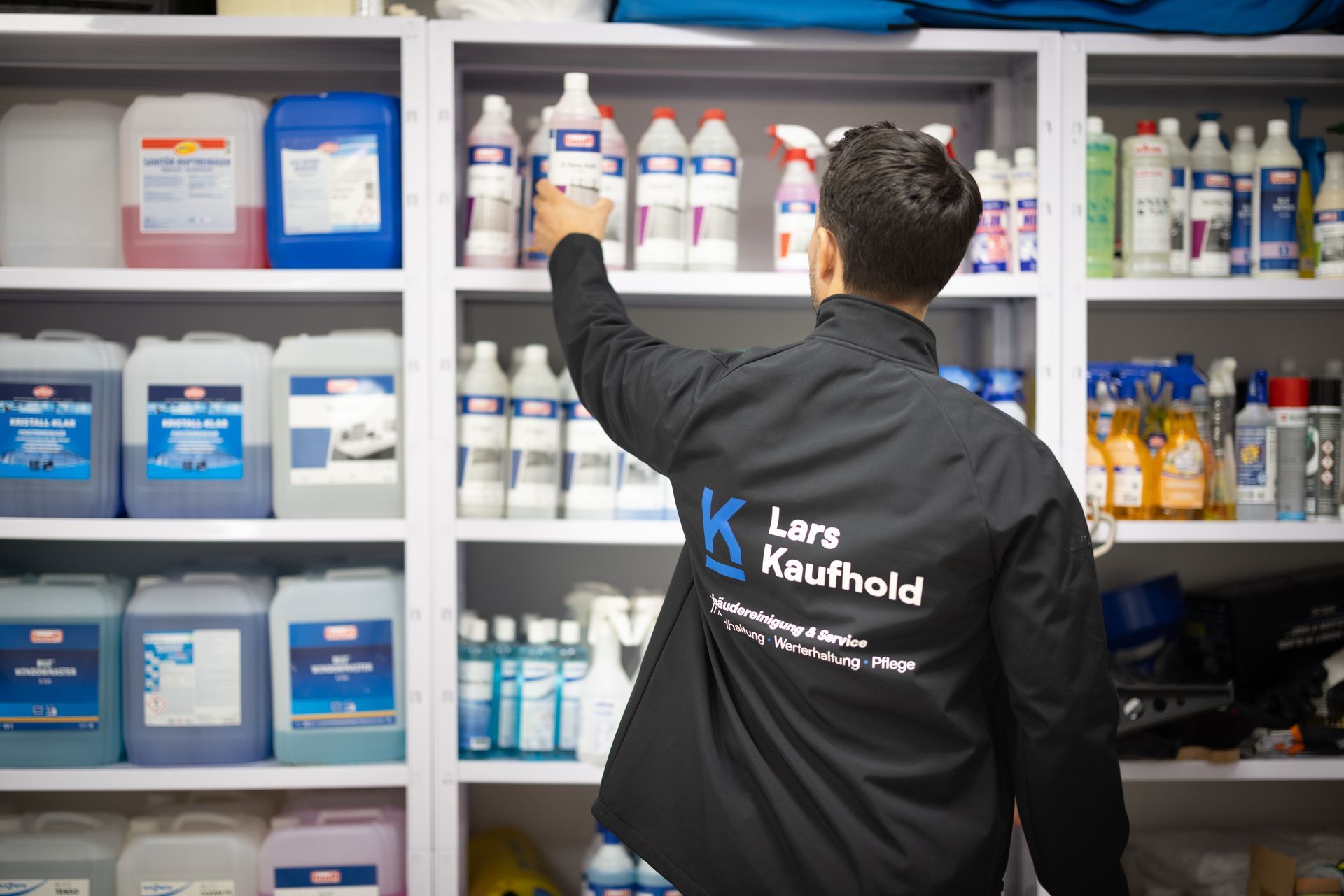 Eine Person wischt die Treppe in einem Gebäude. Er trägt ein schwarzes T-Shirt, Shorts und Turnschuhe.