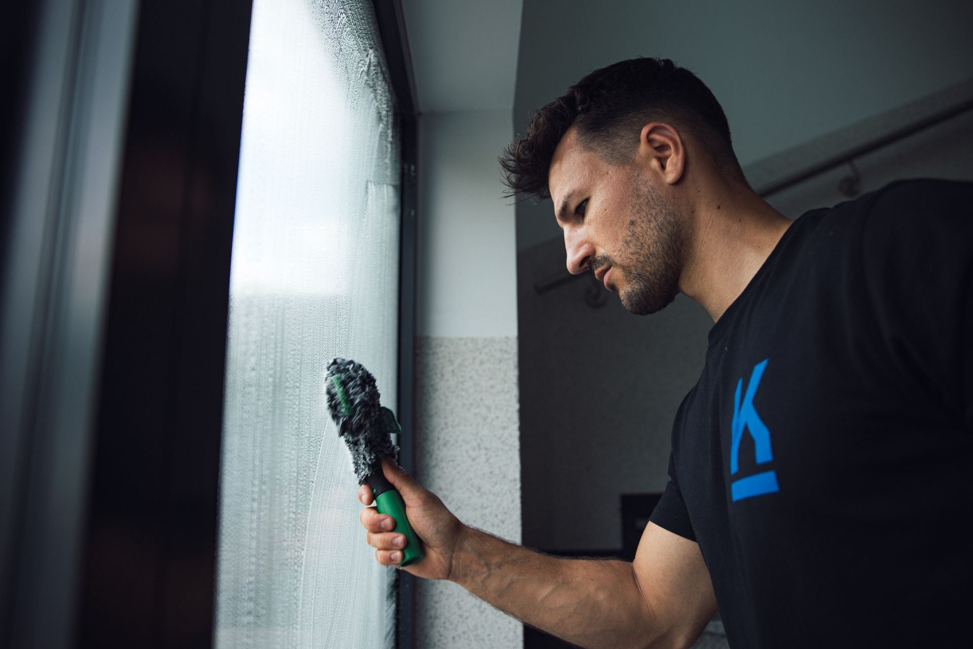 Eine Person wischt die Treppe in einem Gebäude. Er trägt ein schwarzes T-Shirt, Shorts und Turnschuhe.