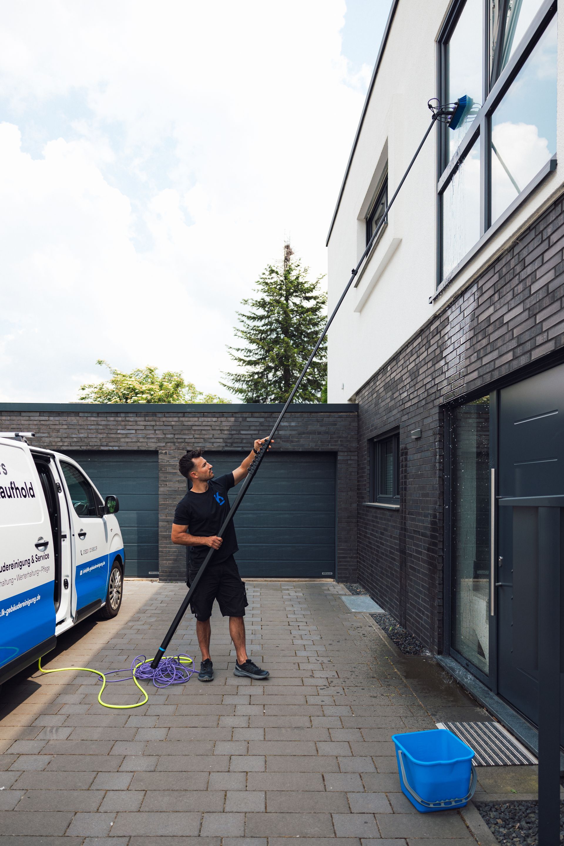 Mann in schwarzer Kleidung wischt einen Hauseingang.