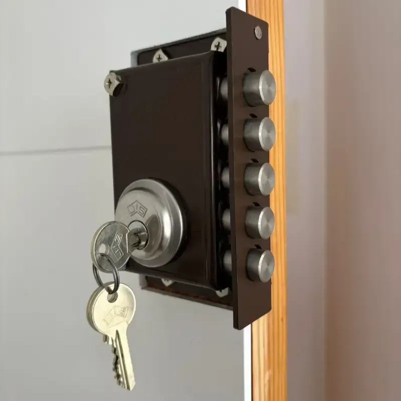 Cerradura de puerta marrón con llave insertada, montada en una puerta blanca.