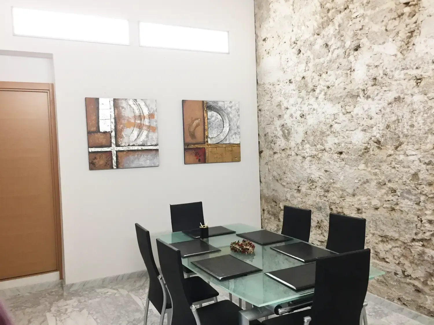 Una sala de reuniones con una mesa de cristal, sillas negras y portátiles.