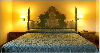 Una cama con una manta azul y un cabecero verde en una habitación de hotel.