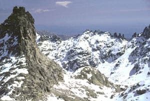 Una montaña cubierta de nieve y rocas con un cielo azul de fondo.