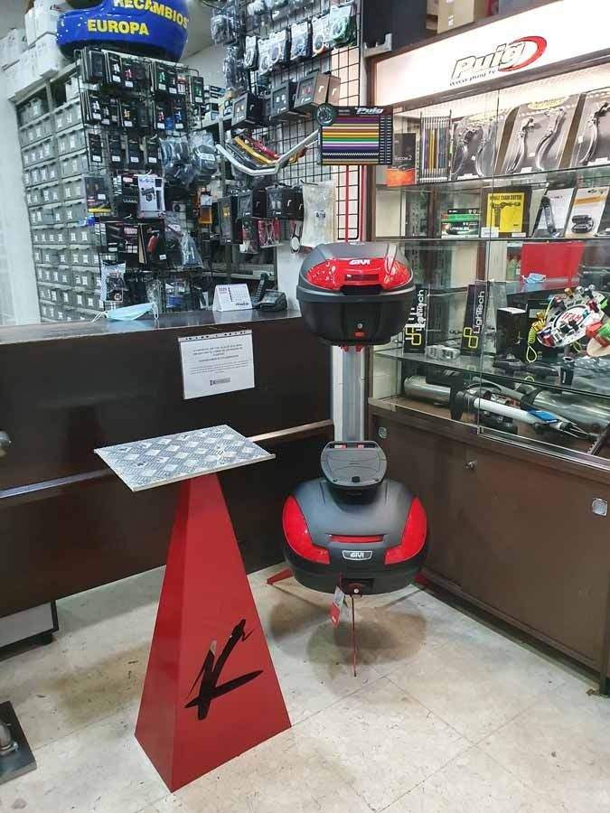 El baúl de una motocicleta está colocado encima de un cono rojo en una tienda.
