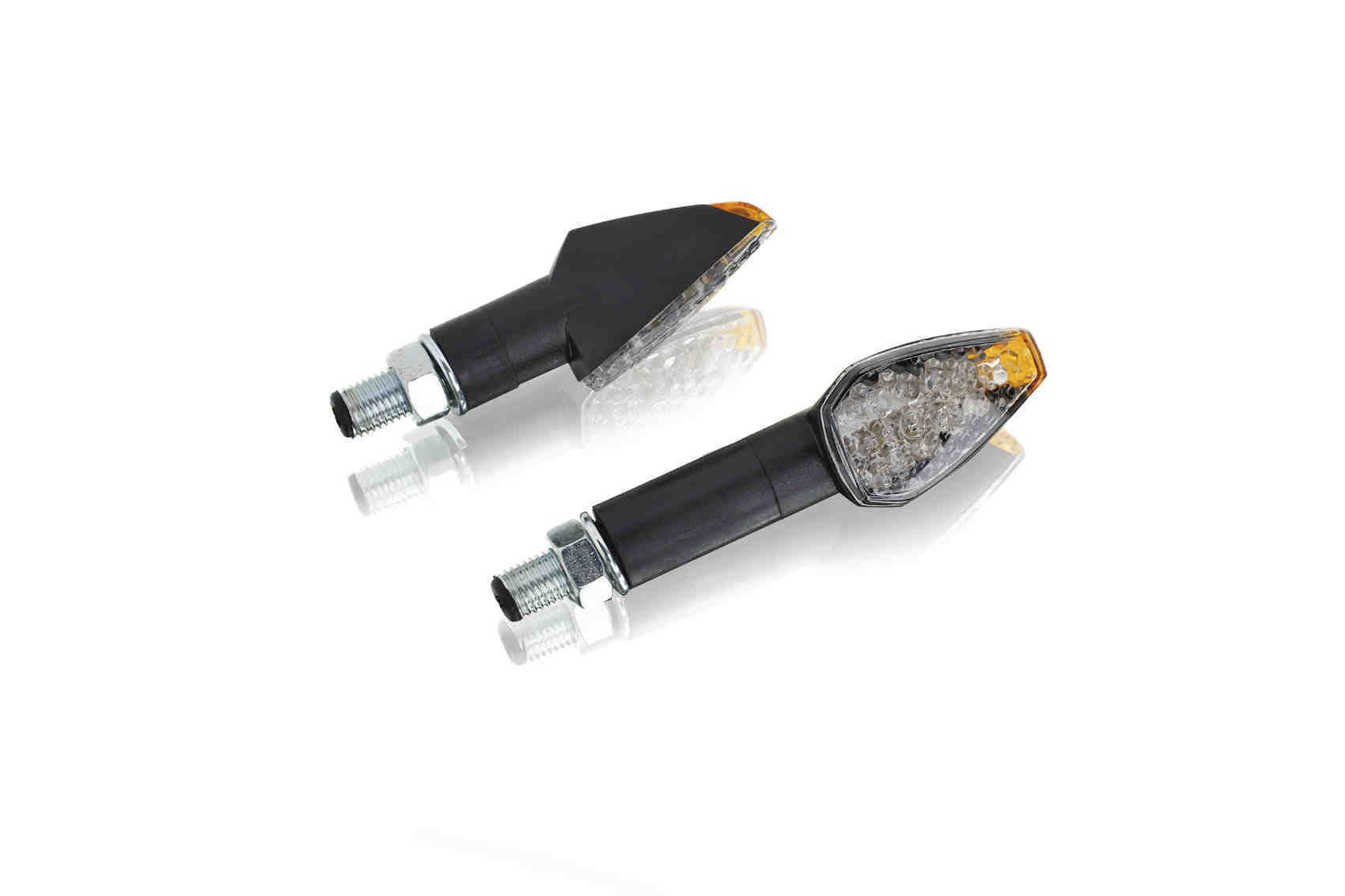 Dos intermitentes de motocicleta negros con lentes ámbar, sobre una superficie blanca.
