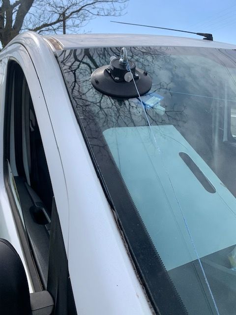 Support à ventouse fixé au pare-brise d'une voiture, avec une feuille de papier bleu à l'intérieur du véhicule.