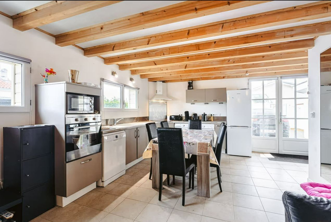 Une cuisine équipée et une salle à manger sous un plafond avec des poutres en bois.
