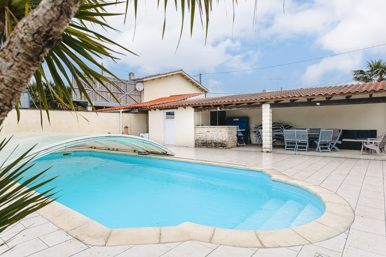 Une piscine chauffée et couverte devant une maison.