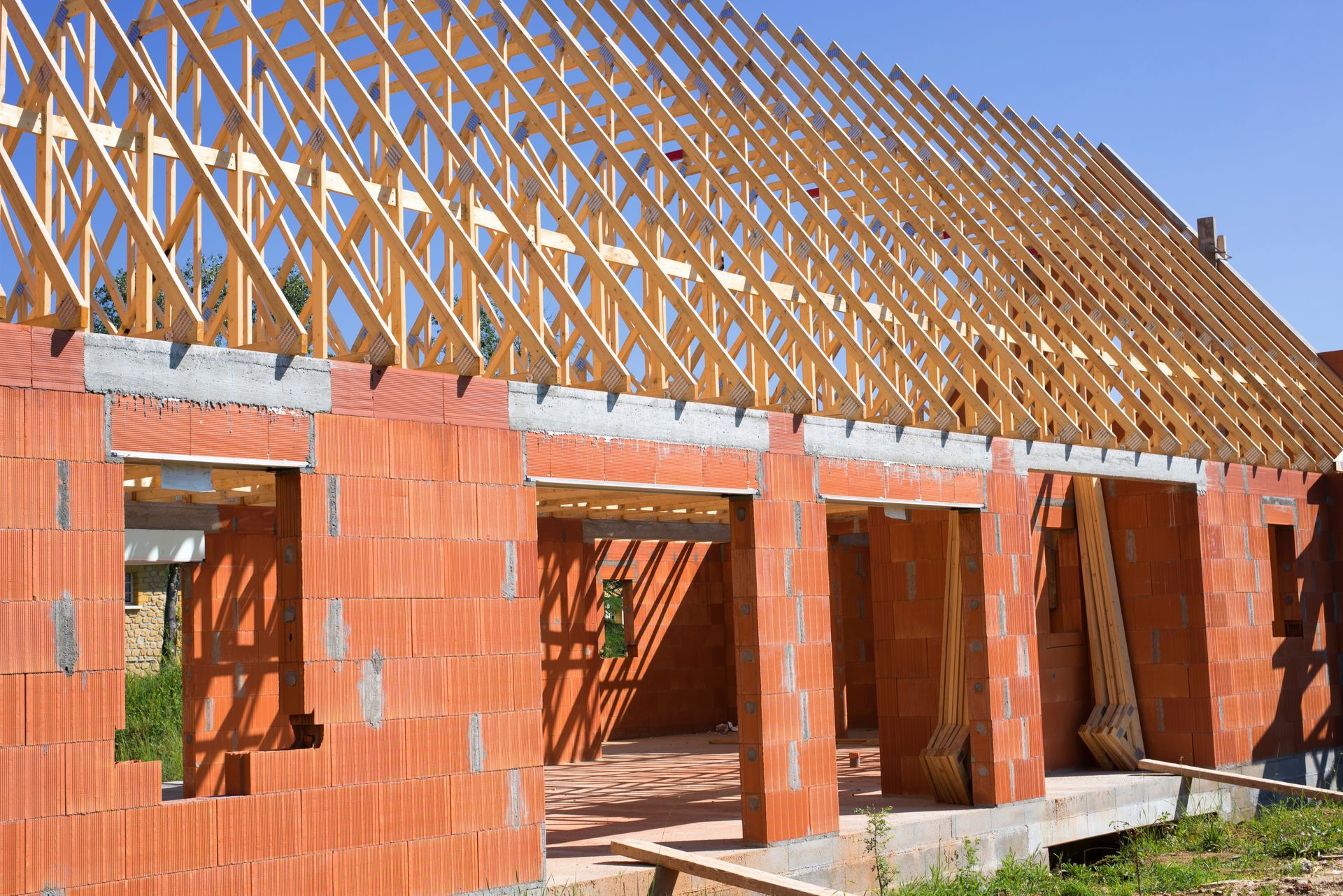 Bâtiment en briques en construction avec charpente apparente en bois.