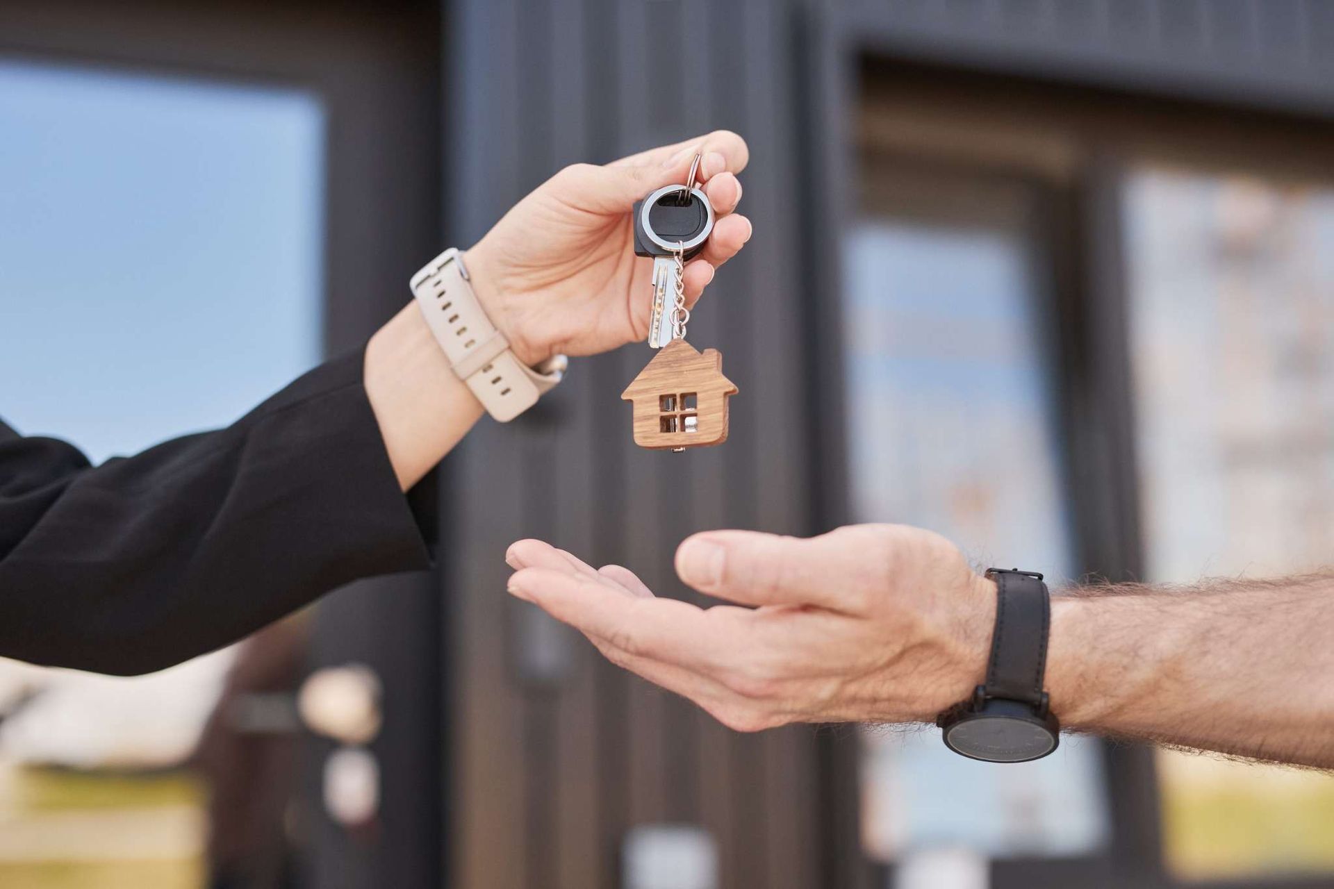 Intercambio de llaves de casa entre dos personas fuera de una vivienda.