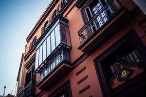 Edificio de ladrillo rojo con balcones de metal negro contra un cielo azul.