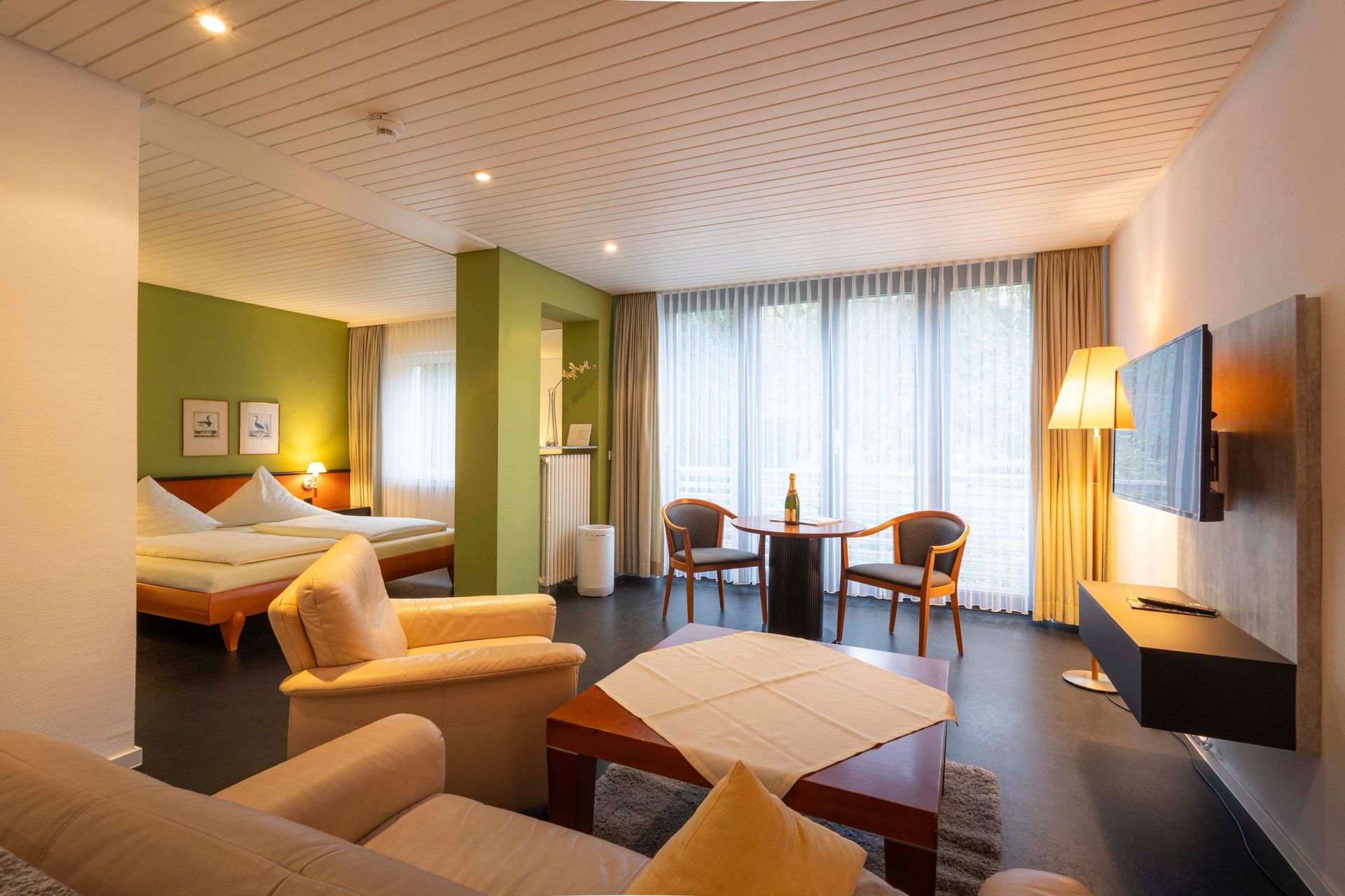 Ein Hotelzimmer mit Couch, Stühlen, Tisch und Fernseher.