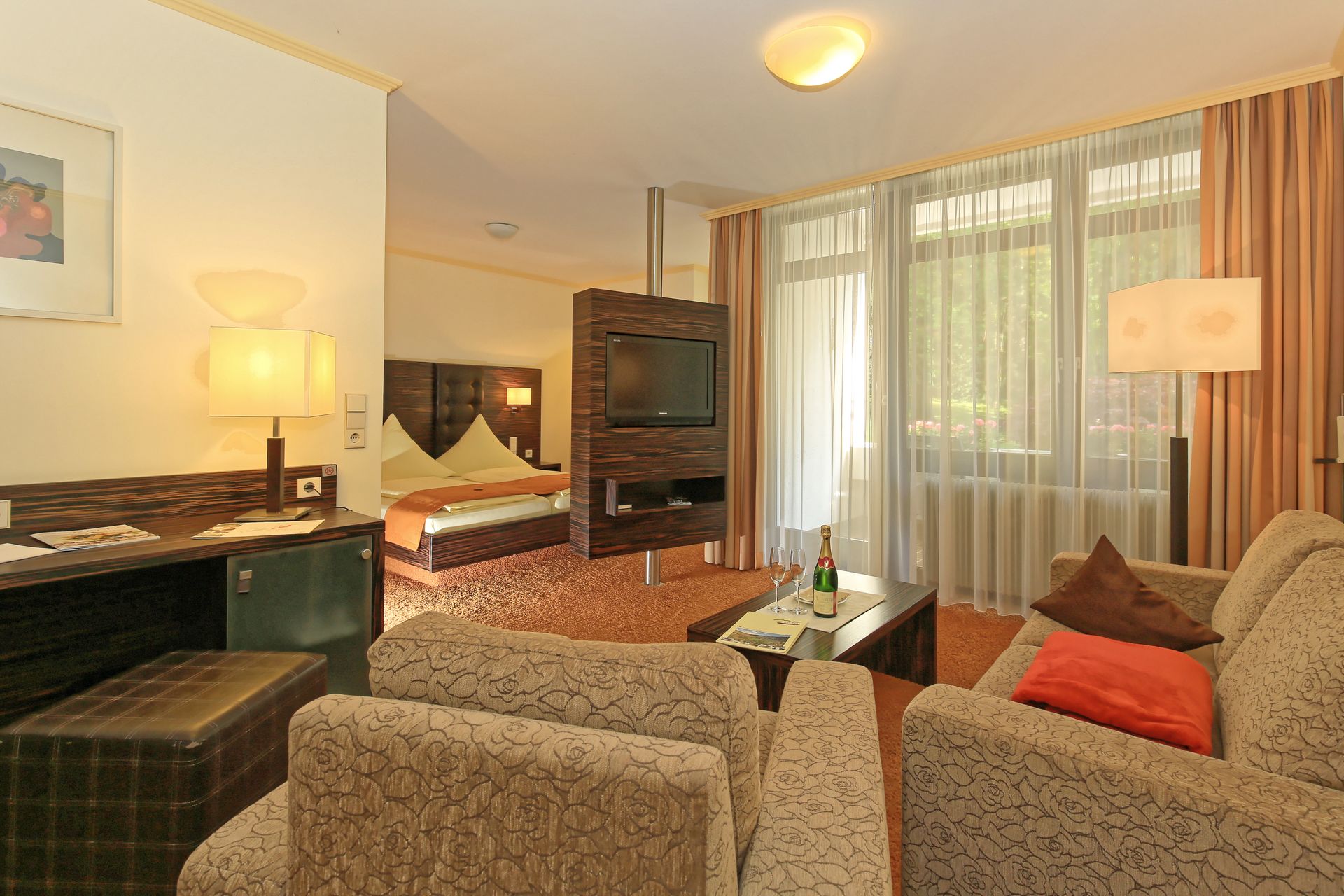 Ein Hotelzimmer mit einer Couch, Stühlen und einem Fernseher