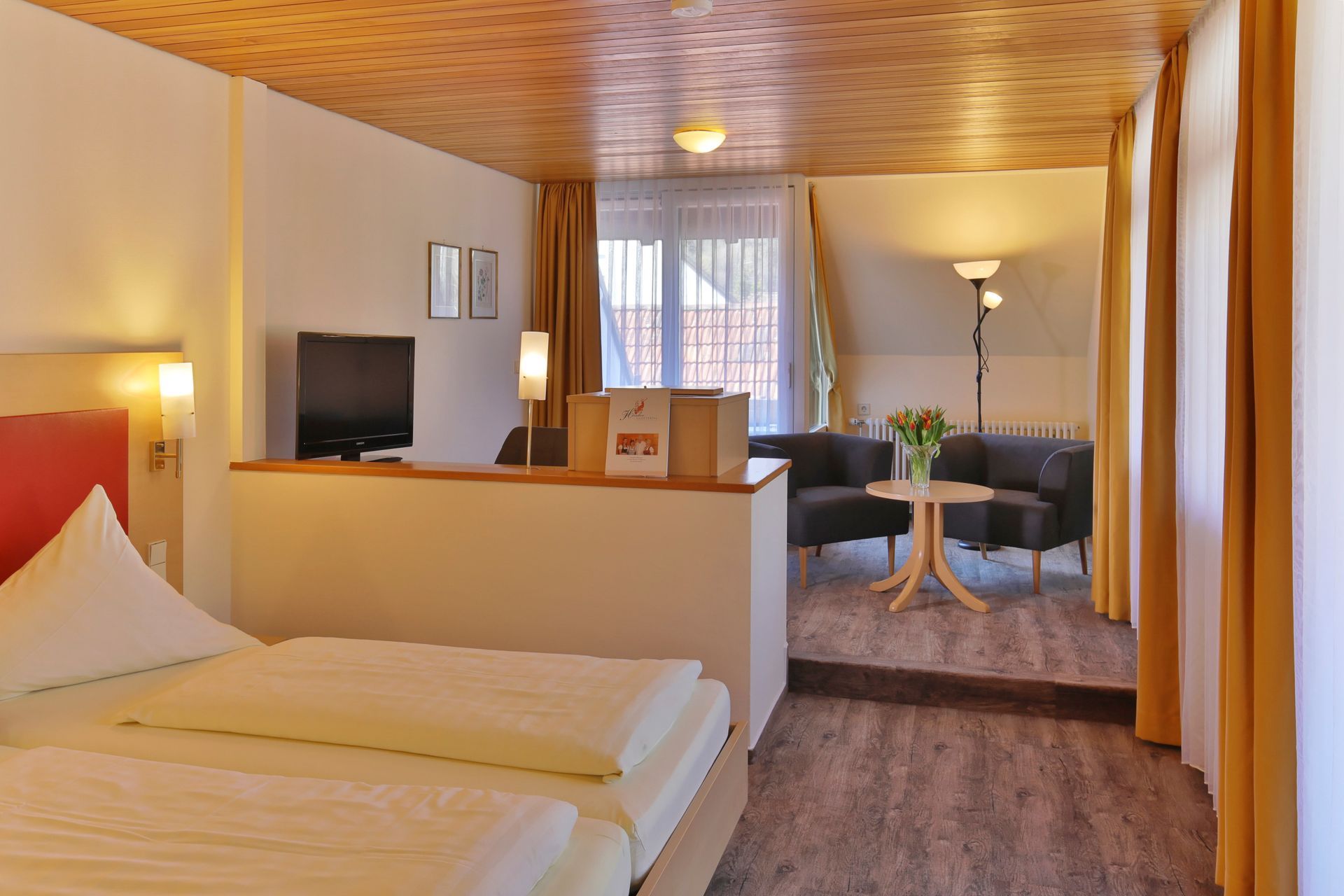 Ein Hotelzimmer mit einem Bett, Fernseher, Stühlen und einem Tisch.