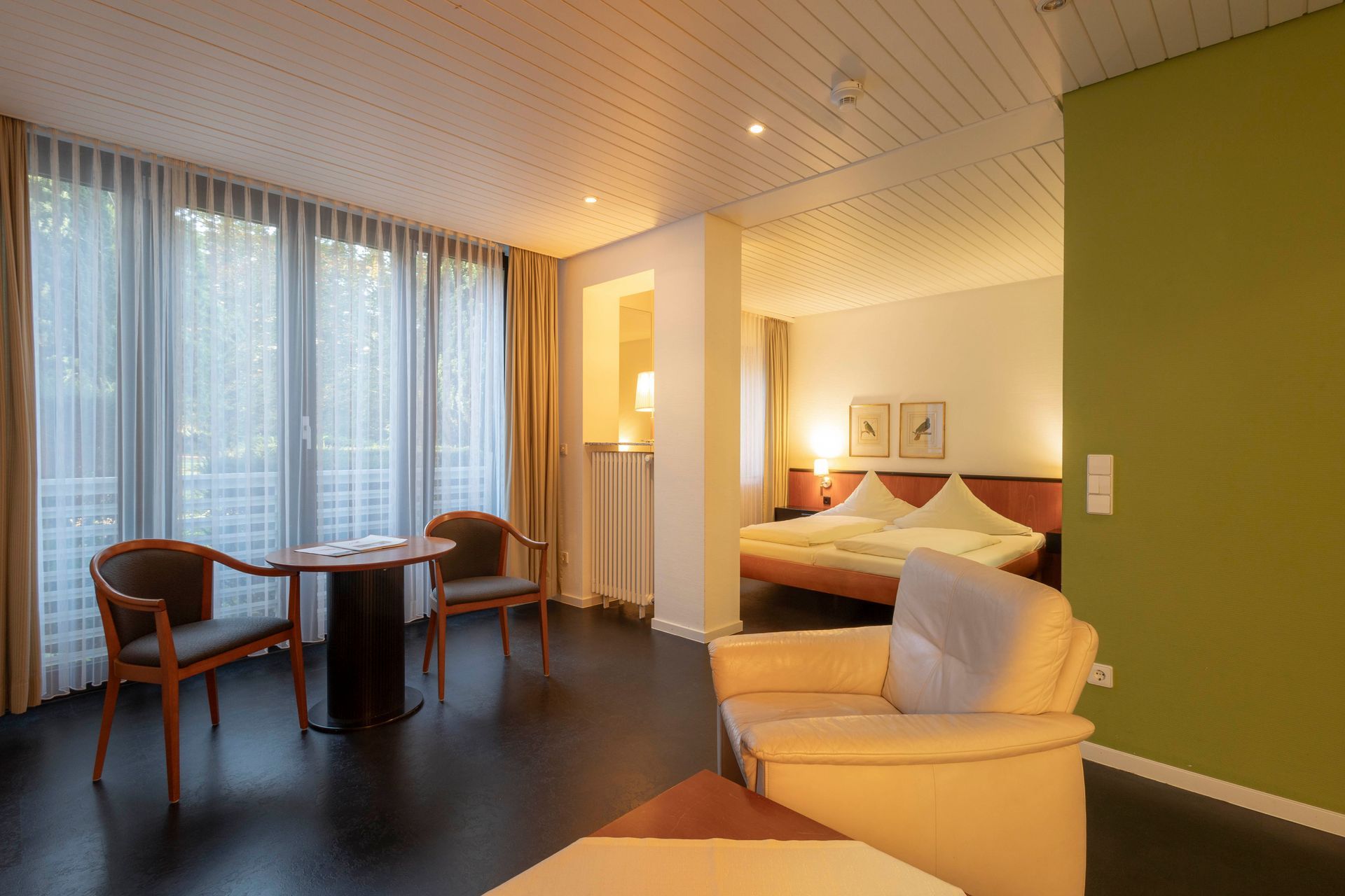 Ein Hotelzimmer mit einem Tisch, Stühlen und einem Bett.