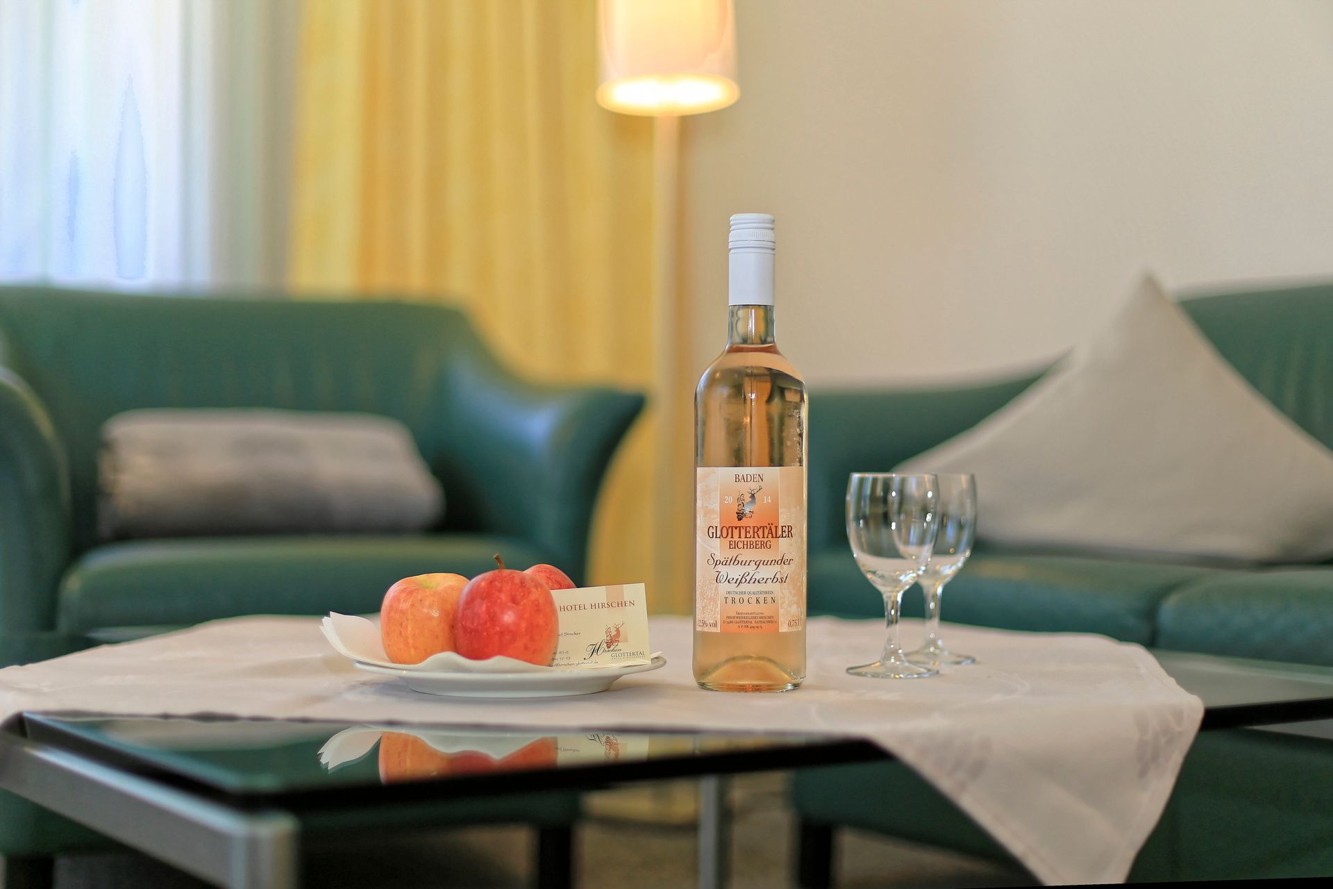 Eine Flasche Wein und zwei Gläser stehen auf einem Tisch in einem Wohnzimmer.