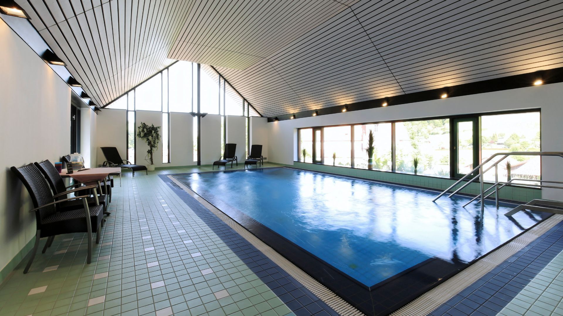 Ein großes Hallenbad mit Liegestühlen drumherum