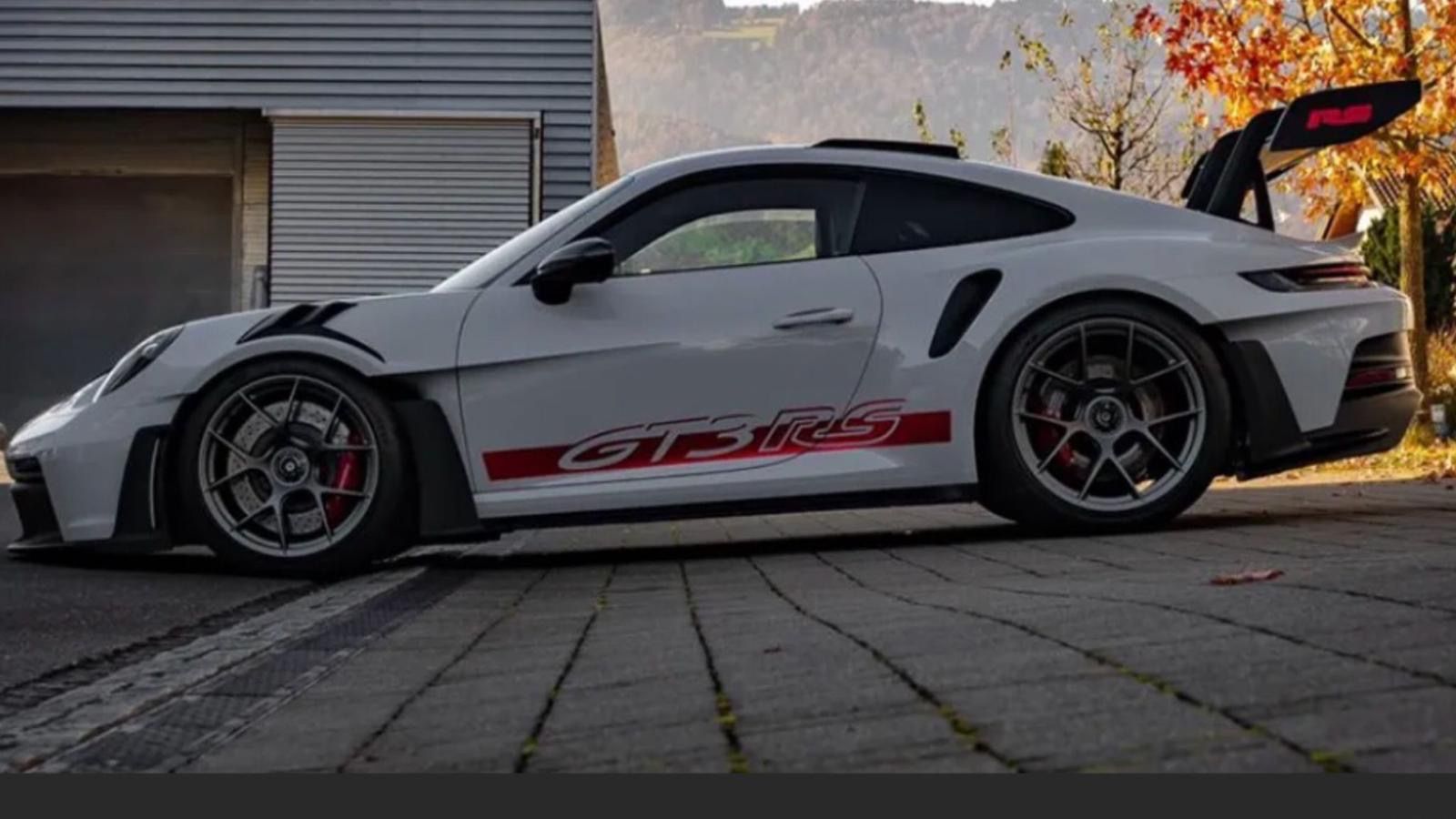 Frau in weißem Outfit sitzt lächelnd in einem weißen Auto, den einen Arm am Lenkrad.