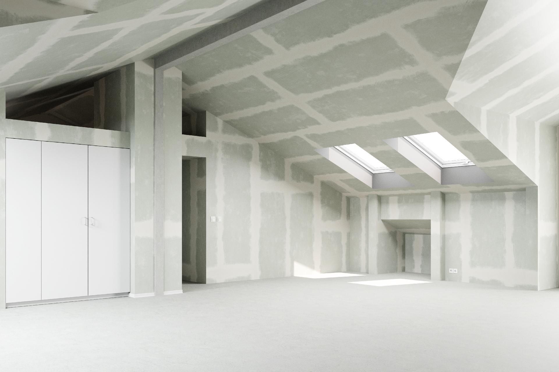 Innenansicht eines im Bau befindlichen Raumes mit freiliegenden Gipskartonwänden und -decke sowie Oberlichtern.
