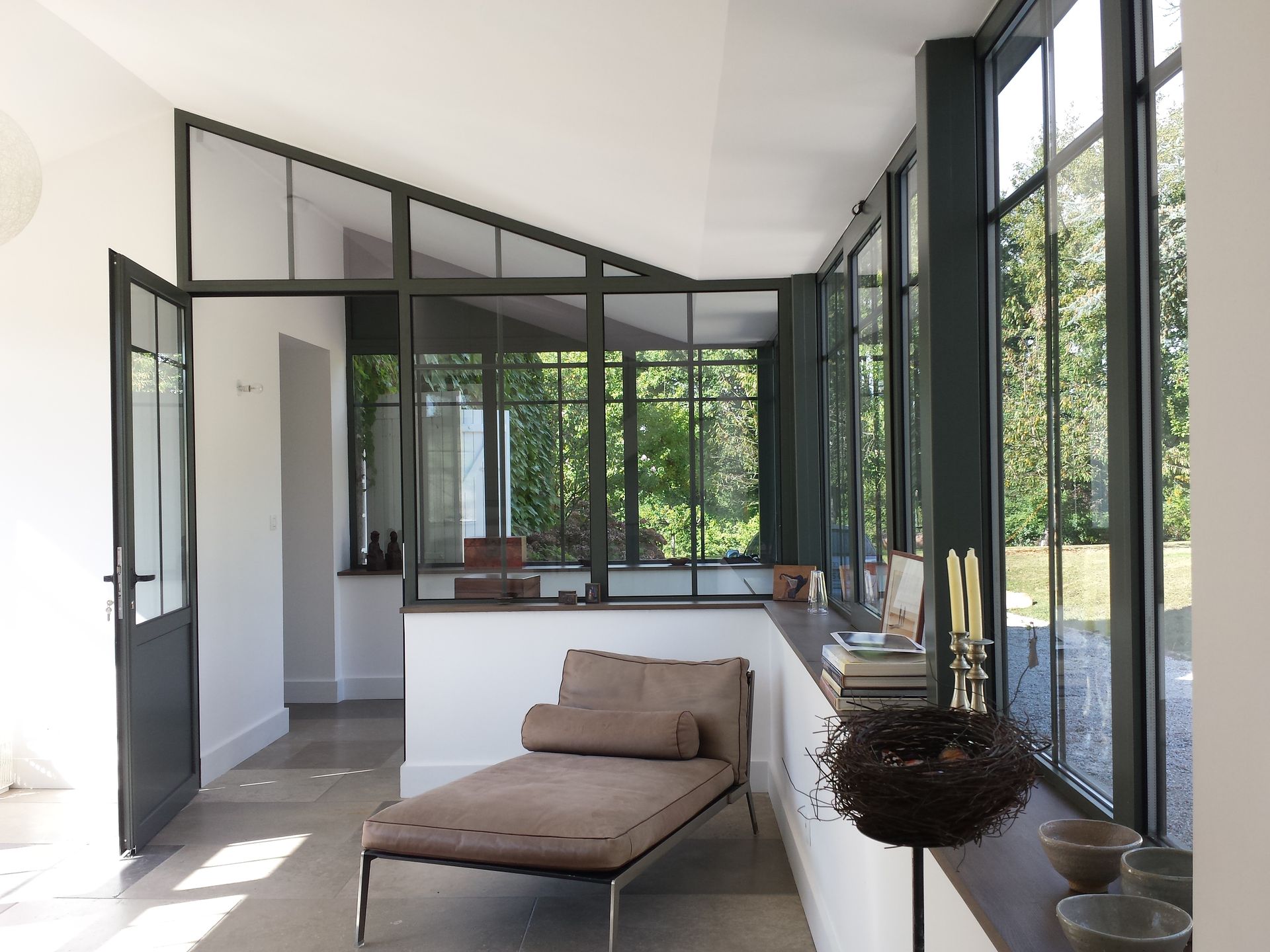 Intérieur d'une extension de maison aux menuiseries sombres aménagée avec du mobilier