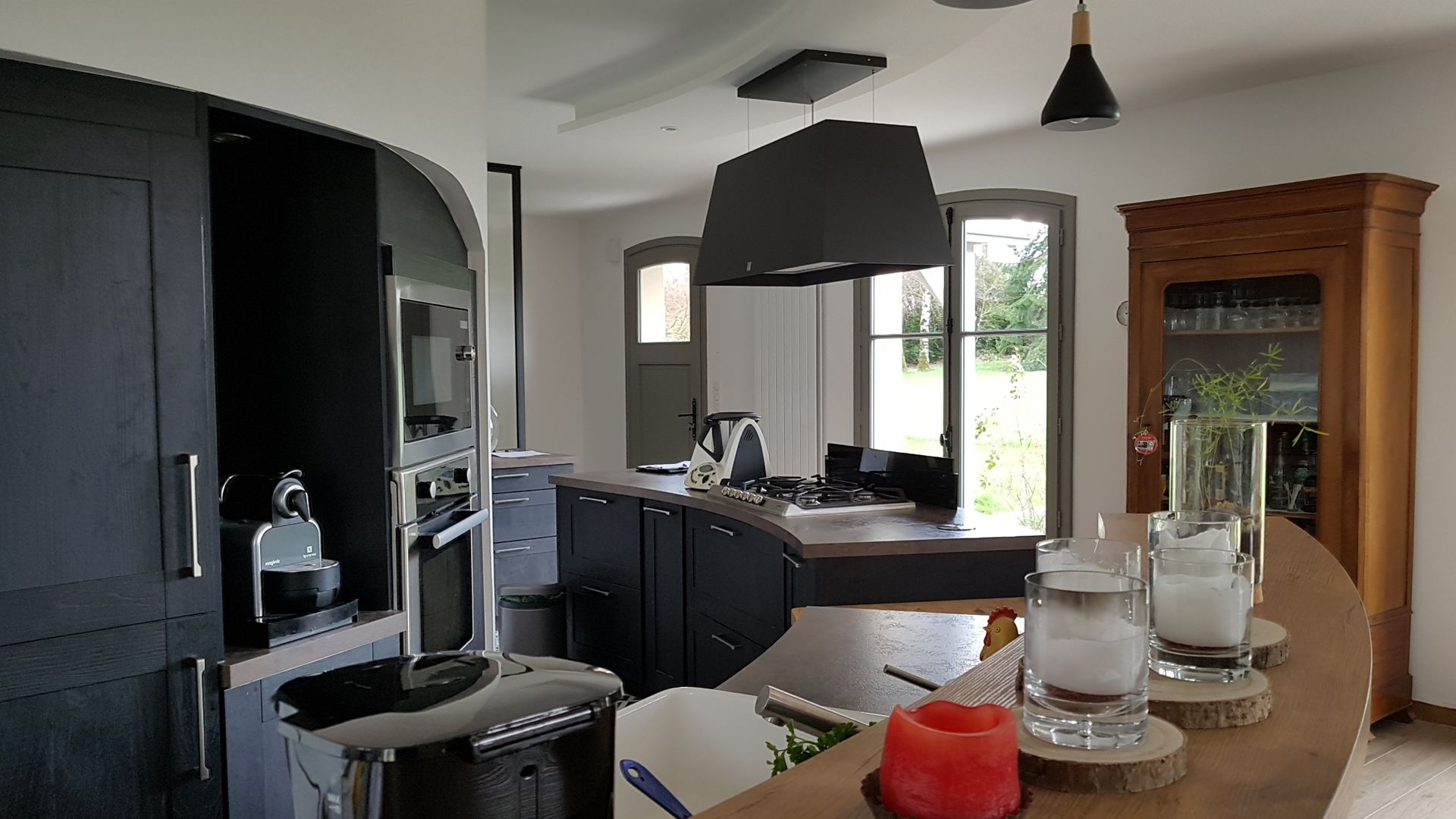 Cuisine noire et bois rénovée avec comptoir, luminaire et mobilier encastré