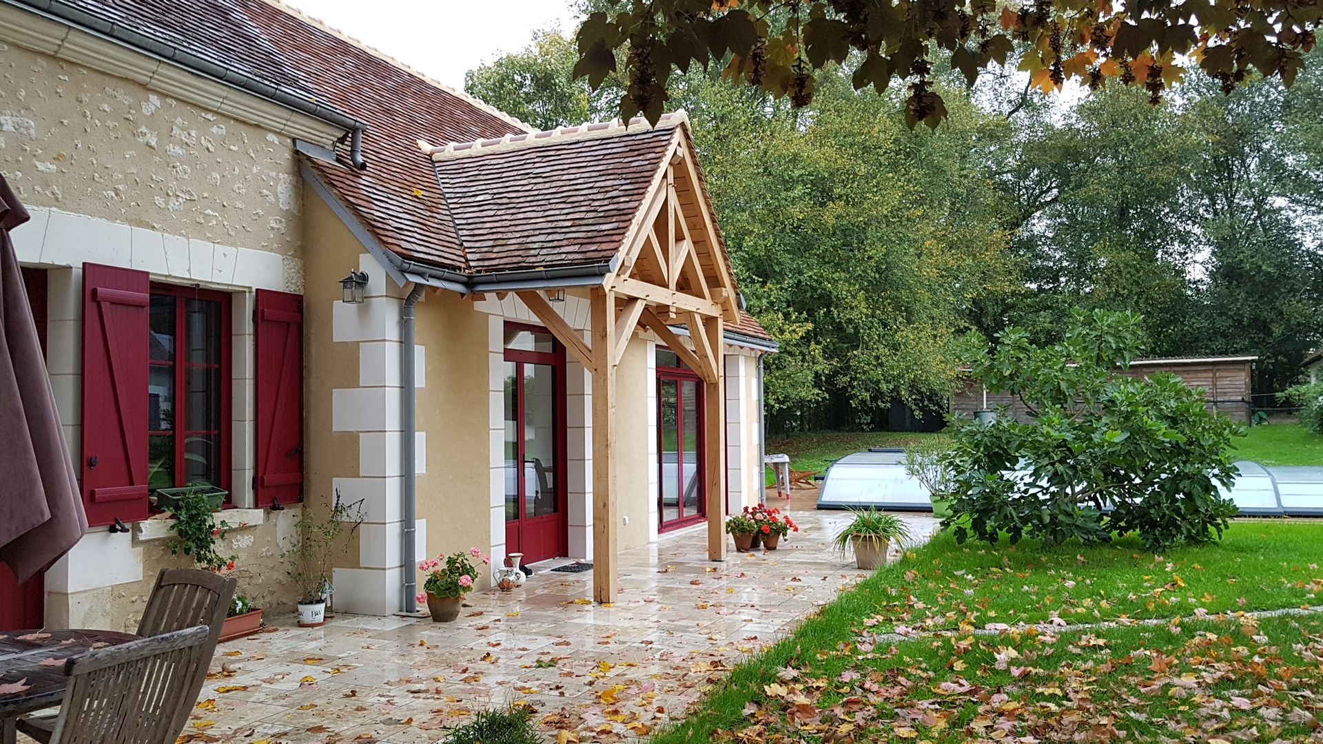 Devanture d'une extension de maison avec fronton en bois, terrasse et menuiseries rouges