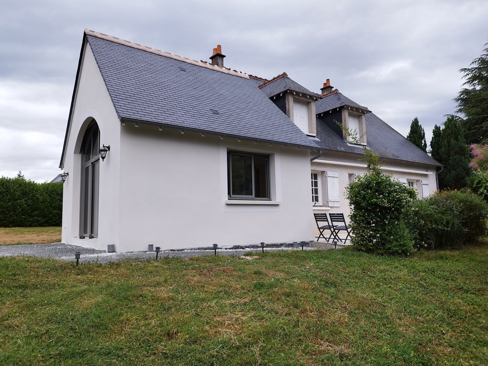 Ajout d'une extension de maison pour un habitat individuel aux murs blancs et au toit en ardoise