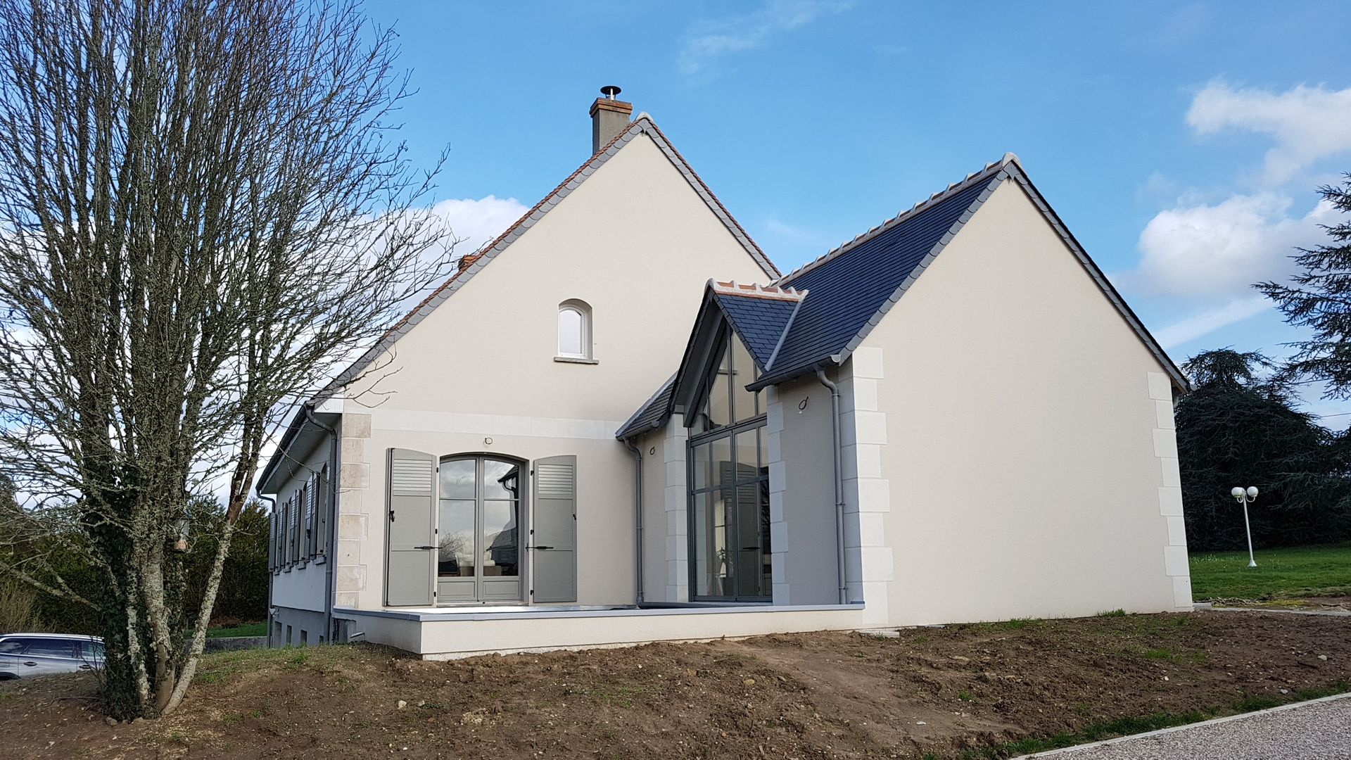 Extension de maison à la toiture bleu sombre mise en place aux côtés d'une maison individuelle