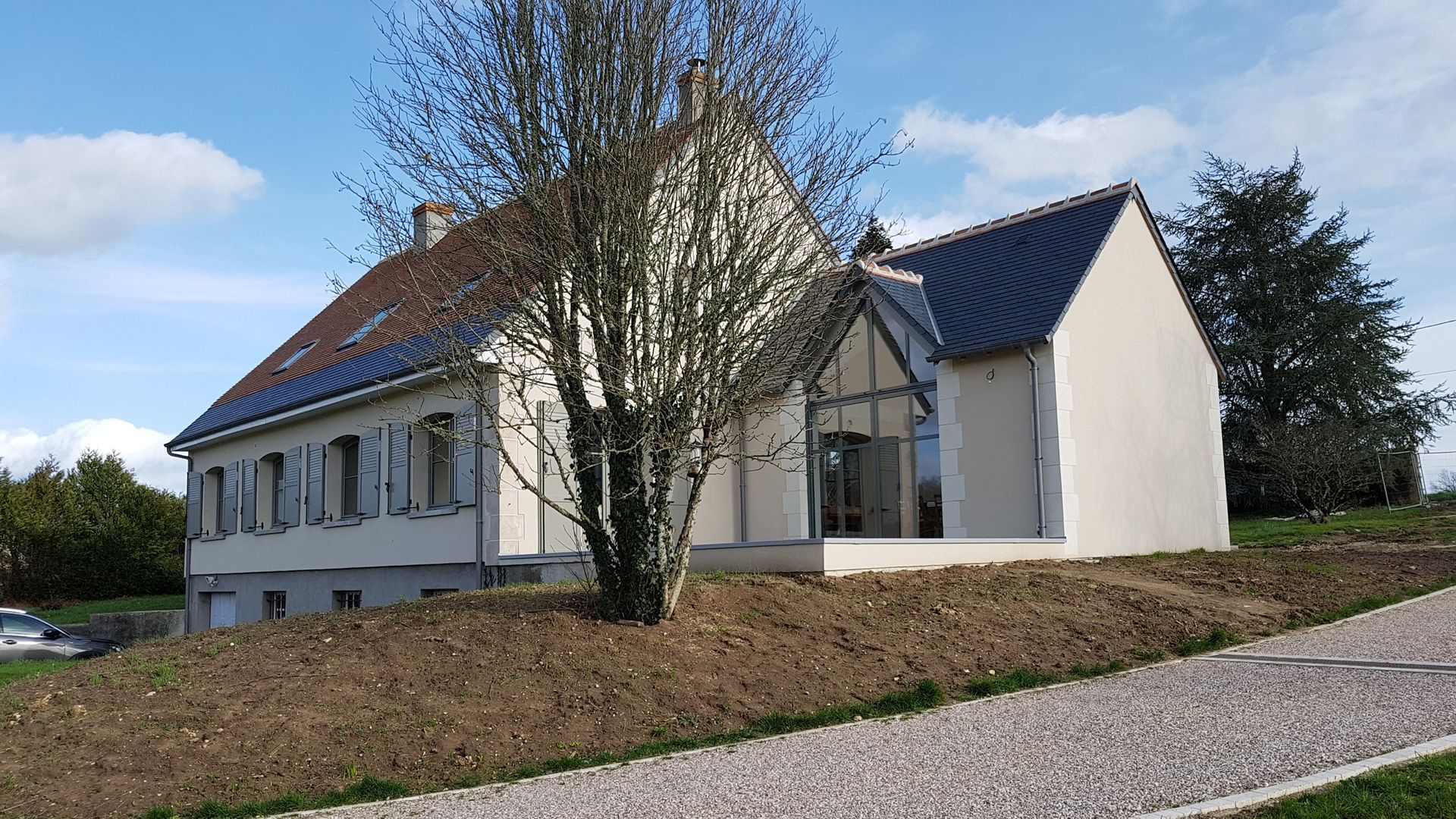 Extension de maison réalisée à droite d'une maison individuelle avec espace laissé devant