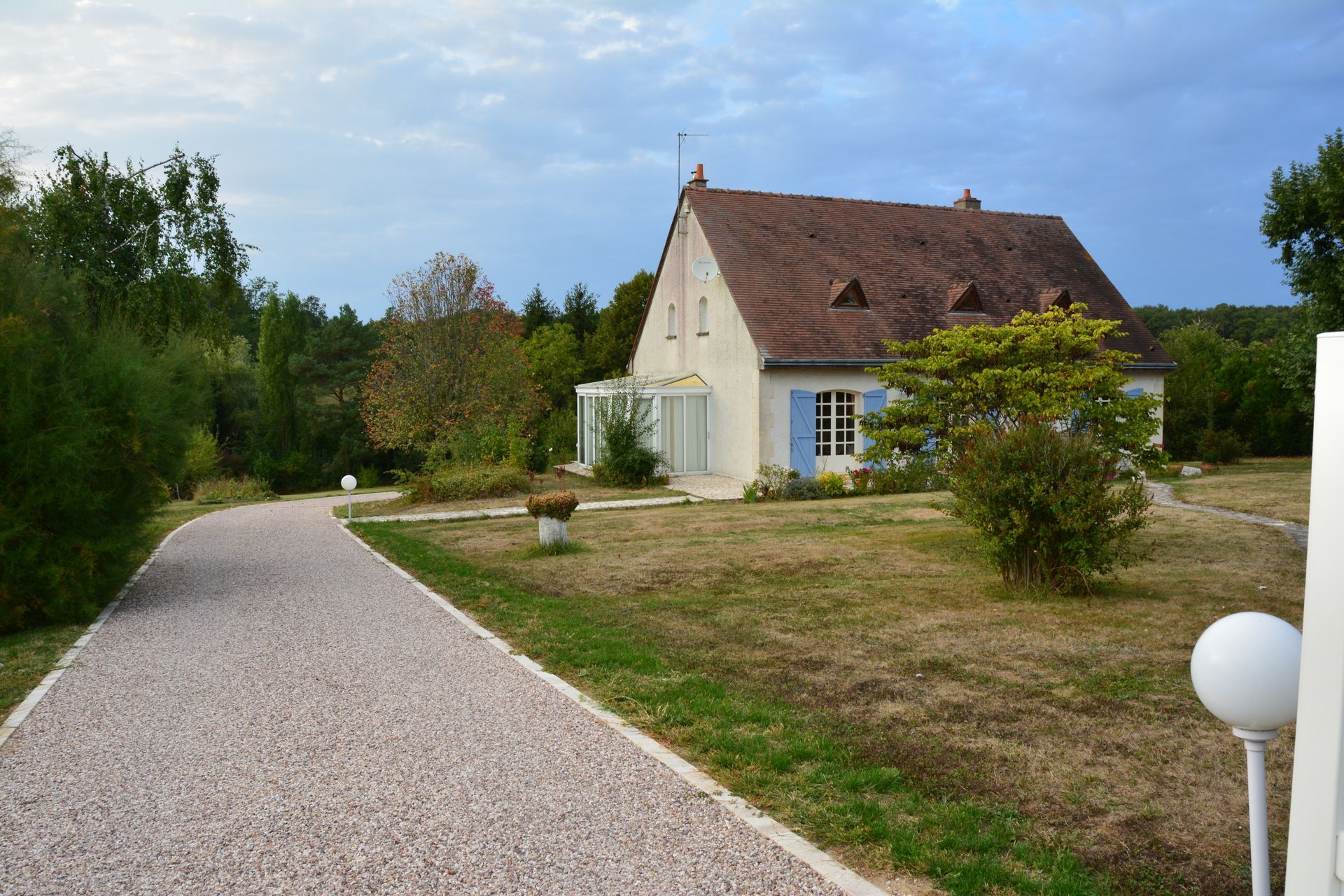 Maison individuelle à rénover avec chemin gravillonné bordé de pelouse