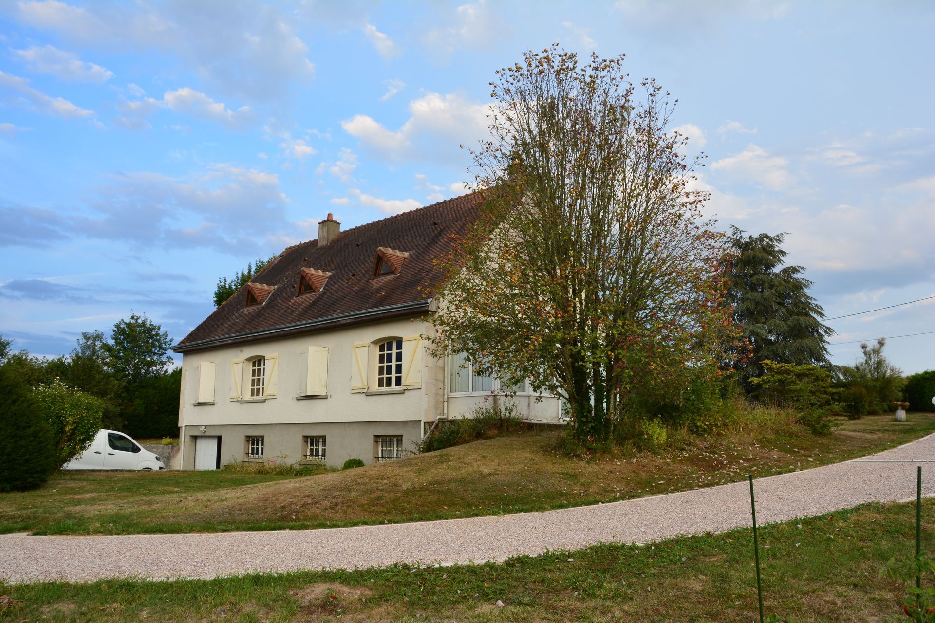 Chemin gravillonné et pelouse devant une maison individuelle à rénover