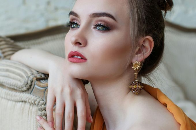 Una donna seduta su un divano indossa orecchini e uno chignon.