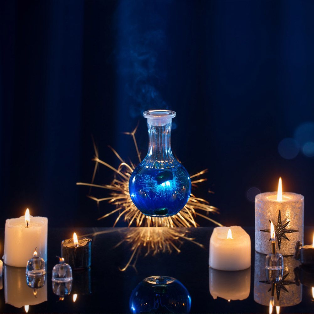 Una botella de líquido azul está rodeada de velas encendidas.