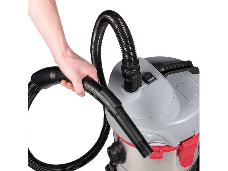 Eine Person hält einen an einen Staubsauger angeschlossenen Schlauch.
