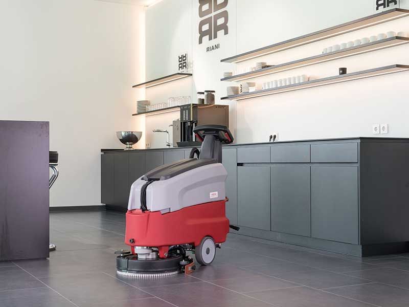 Eine rot-graue Maschine reinigt den Boden in einer Küche