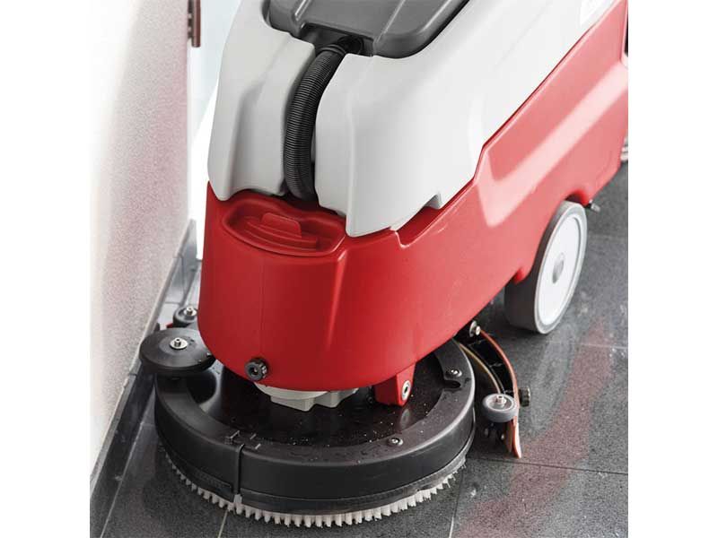 Eine rot-weiße Maschine reinigt einen Fliesenboden