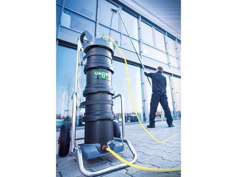 Ein Mann putzt die Fenster eines Gebäudes mit einem Staubsauger