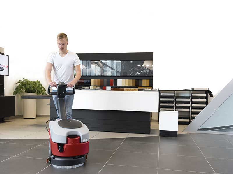 Ein Mann benutzt eine Maschine, um den Boden in einem Raum zu reinigen.