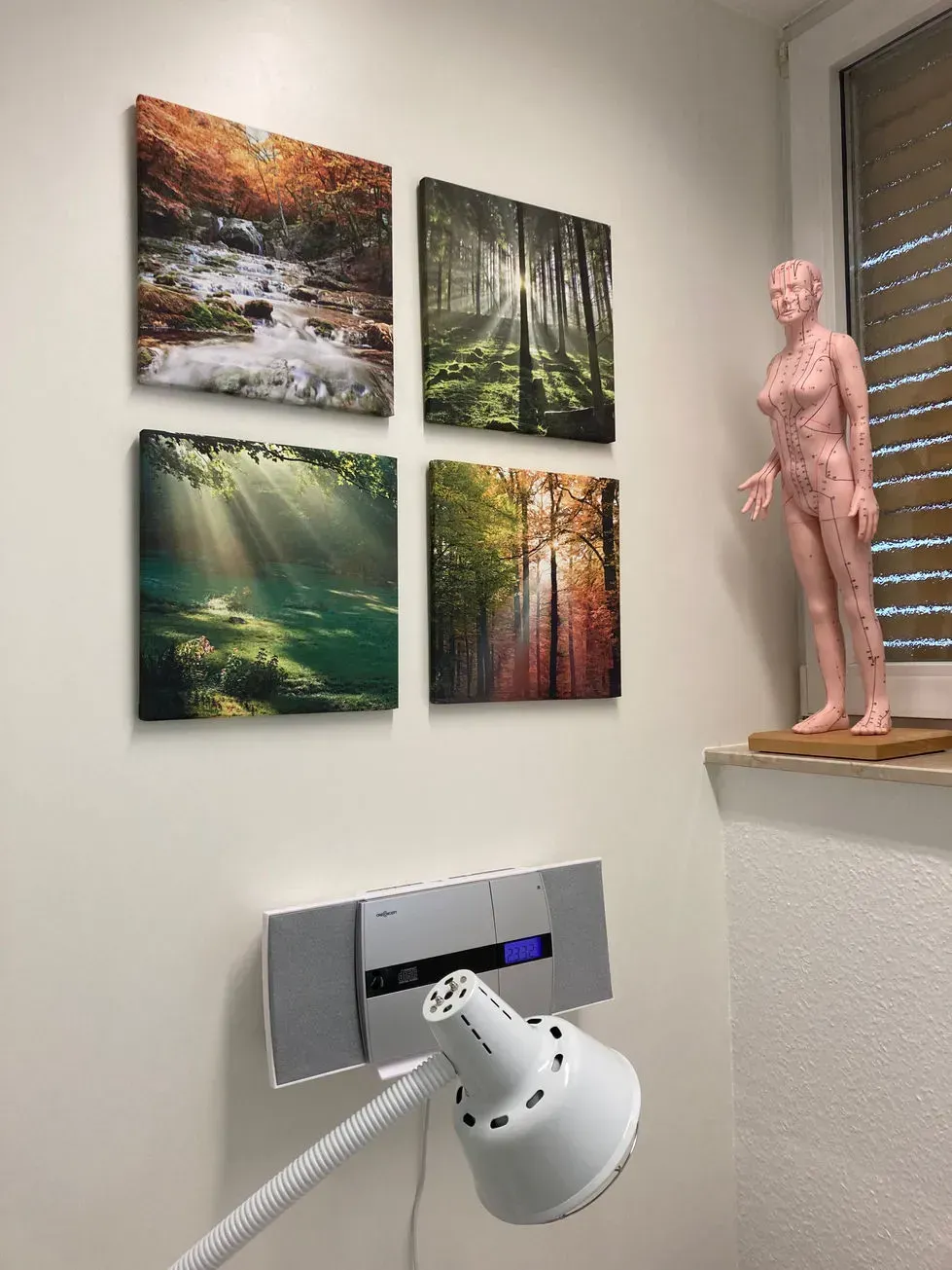 Ein Raum mit vier Gemälden an der Wand und einer Lampe.