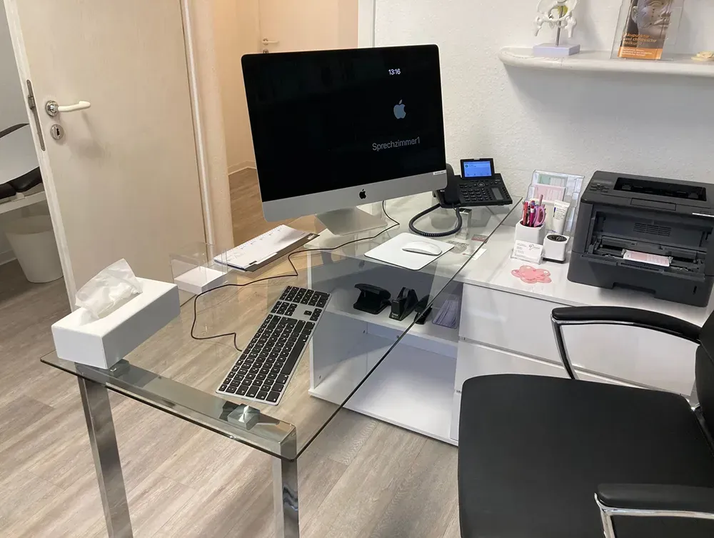 Ein Schreibtisch mit einem Computer, einer Tastatur und einem Drucker darauf.