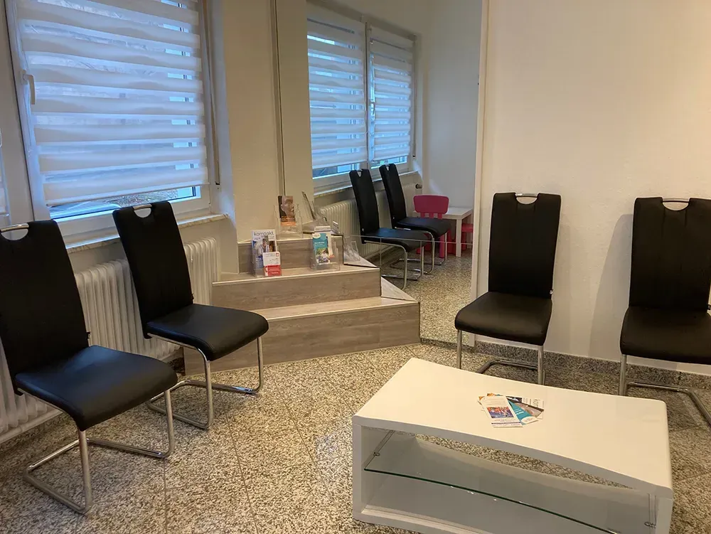 Ein Wartezimmer mit schwarzen Stühlen und einem weißen Couchtisch.