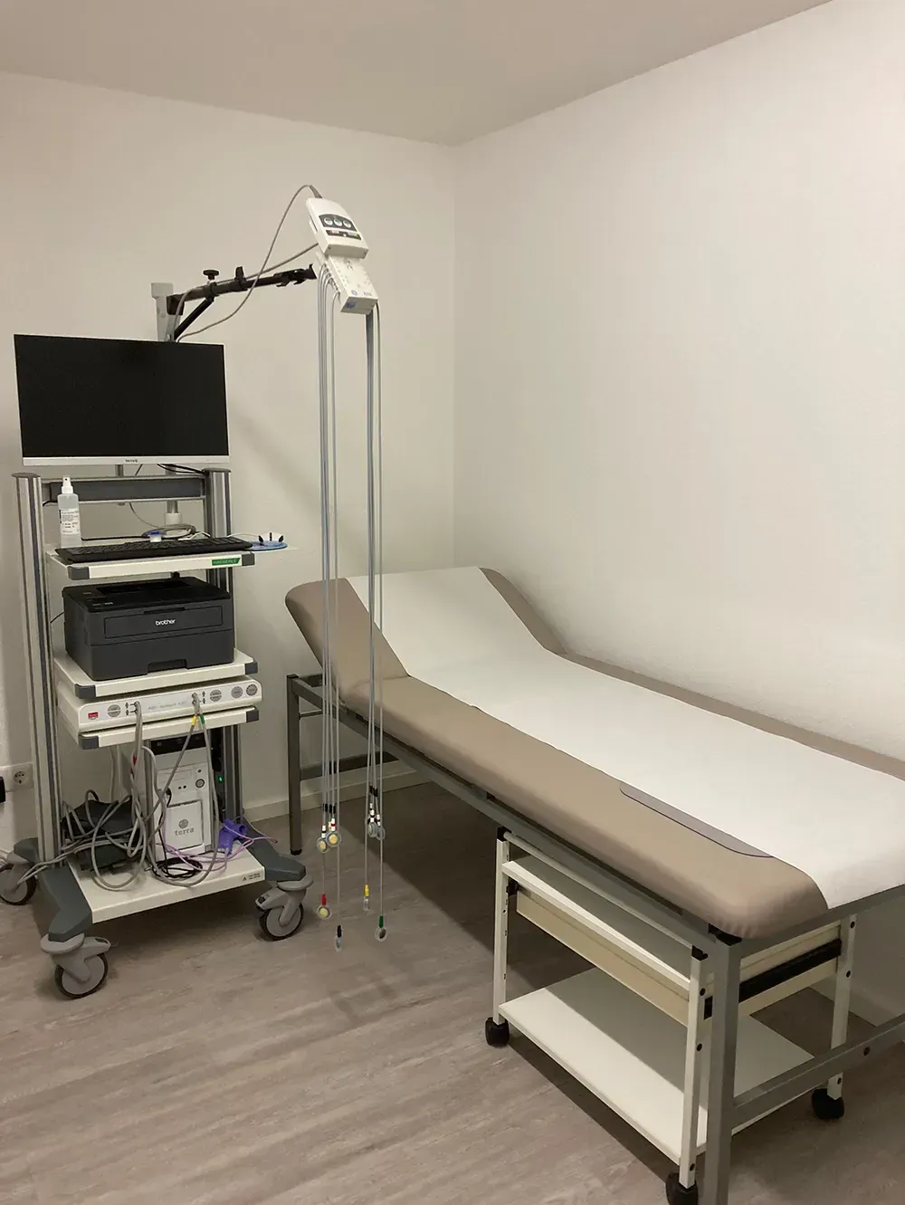 Eine Arztpraxis mit einem Bett und einem Computer auf einem Wagen.